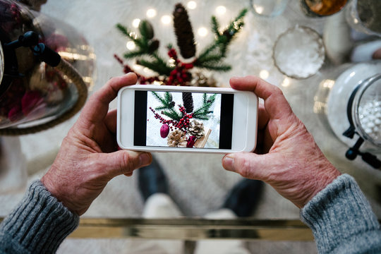 Senior man taking a picture of Christmas decoration with the phone