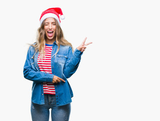 Beautiful young blonde woman wearing christmas hat over isolated background smiling with happy face...
