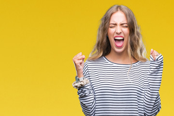 Beautiful young blonde woman wearing stripes sweater over isolated background excited for success with arms raised celebrating victory smiling. Winner concept.