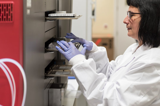 Female scientist working with a genome sequencing machine in a DNA laboratory