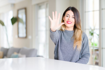 Young beautiful woman wearing winter sweater at home showing and pointing up with fingers number five while smiling confident and happy.