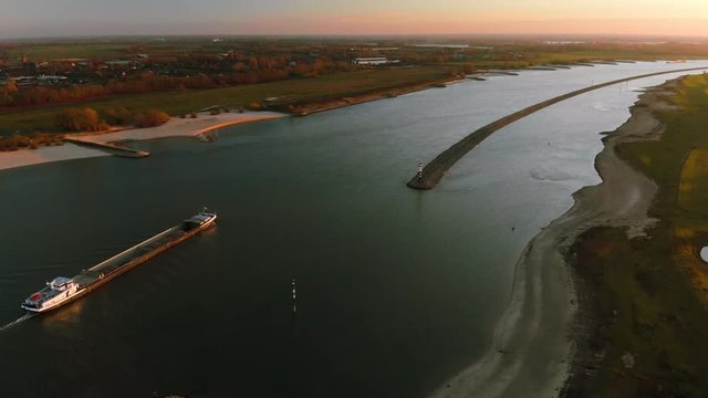Aerial view: cargo transport ship with sand sailing downriver (Waal) during sunset, Fall The Netherlands