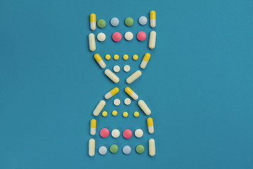pills on a blue background in the form of DNA chain