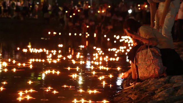 Woman placing a burning candle into the water. Loy Krathong Festival, Thailand.