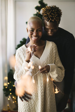 Portrait of multiethnic couple celebrating Christmas at home. 