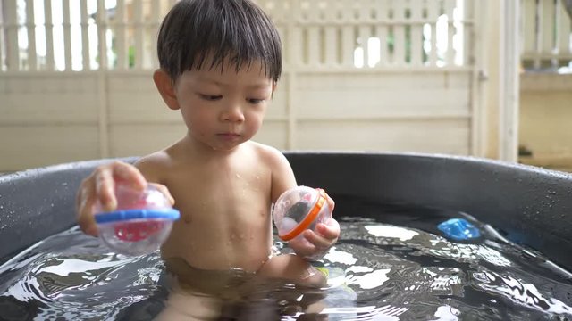 slow motion, cute child playing toy in small water pool bath time