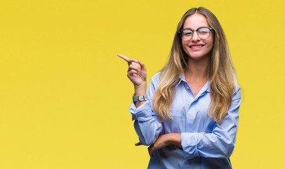 Young beautiful blonde business woman wearing glasses over isolated background with a big smile on face, pointing with hand and finger to the side looking at the camera.