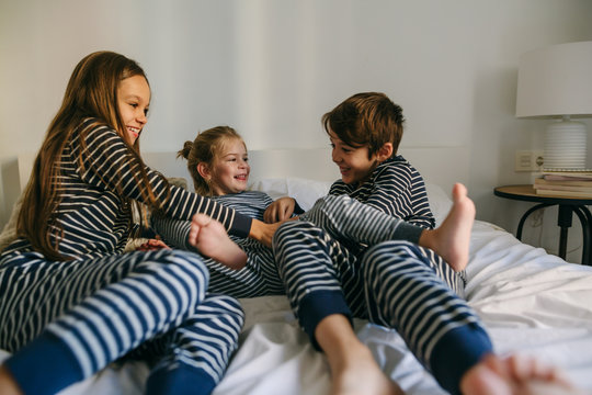 Naklejki Kids wearing pajama playing on bed. 
