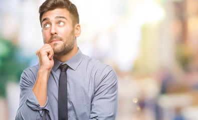 Young handsome business man over isolated background with hand on chin thinking about question, pensive expression. Smiling with thoughtful face. Doubt concept.