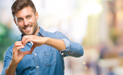 Young handsome man over isolated background smiling in love showing heart symbol and shape with hands. Romantic concept.