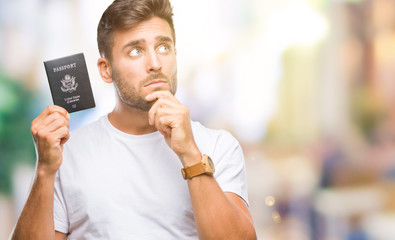 Young handsome man holding passport of united states over isolated background serious face thinking...