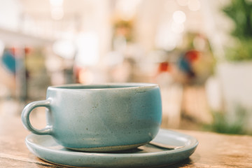 Ceramic Pastel Blue Tea cup on the wooden table with blur cafe background soft focus