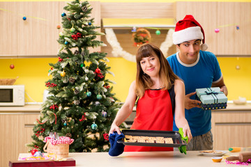 Obraz na płótnie Canvas Young couple celebrating Christmas in kitchen 