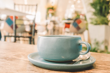 Ceramic Pastel Blue Tea cup on the wooden table with blur cafe background soft focus