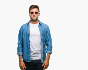 Fototapeta premium Young handsome man wearing sunglasses over isolated background with serious expression on face. Simple and natural looking at the camera.