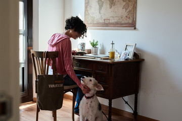 Woman caressing dog while working