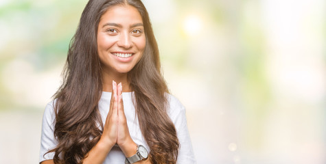 Young beautiful arab woman over isolated background praying with hands together asking for forgiveness smiling confident.