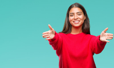 Young beautiful arab woman wearing winter sweater over isolated background looking at the camera smiling with open arms for hug. Cheerful expression embracing happiness.