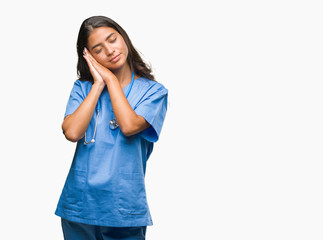 Young arab doctor surgeon woman over isolated background sleeping tired dreaming and posing with hands together while smiling with closed eyes.