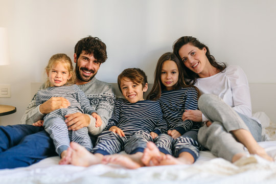 Portrait Of Happy Family Wearing Pajama On Bed. 