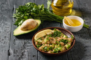 Salad of amaranth seeds, avocado, lemon and parsley with olive oil on a rustic table.