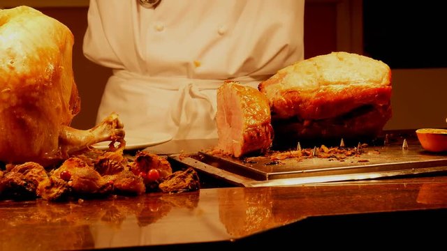 English pub carvery chef cutting slices of roast gammon and turkey and puts them into customer's plate as well as piece of Yorkshire pudding