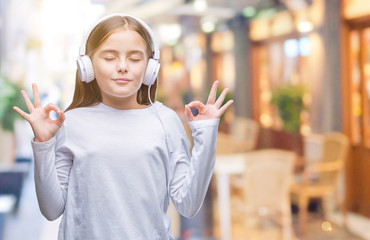 Young beautiful girl wearing headphones listening to music over isolated background relax and...