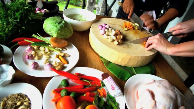 Asian cooking class cutting raw vegetables on wooden chopping board with knives and Balinese Blakas in Indonesia 