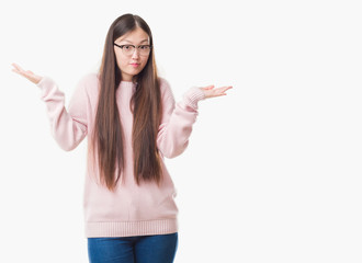 Young Chinese woman over isolated background wearing glasses clueless and confused expression with arms and hands raised. Doubt concept.