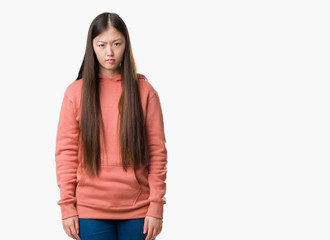 Young Chinese woman over isolated background wearing sport sweathshirt skeptic and nervous, frowning upset because of problem. Negative person.