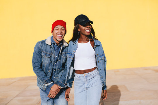 Portrait of cool couple wearing denim clothes in yellow wall. 