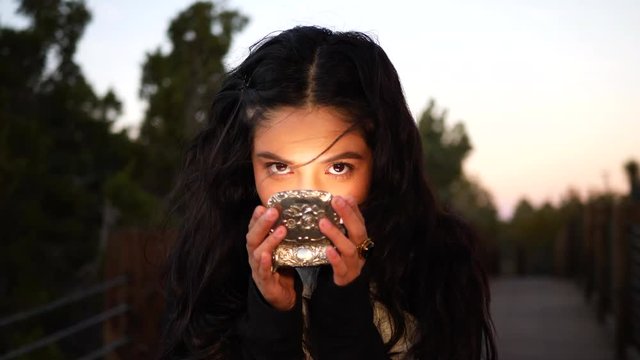 A beautiful mysterious girl staring with her eyes intensely with a mischievous glare over a magic shining silver jewelry box.