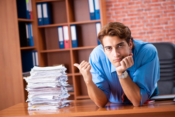 Young employee with excessive work sitting at the office 
