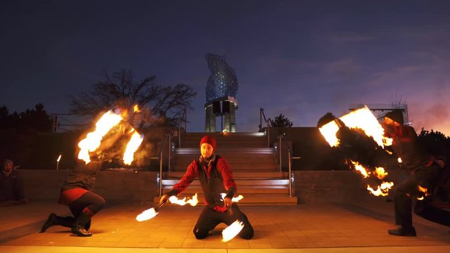 Public fire performance with performers throwing staffs over each other