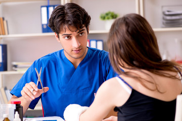 Obraz premium Young woman with bandaged arm visiting male doctor traumotologis