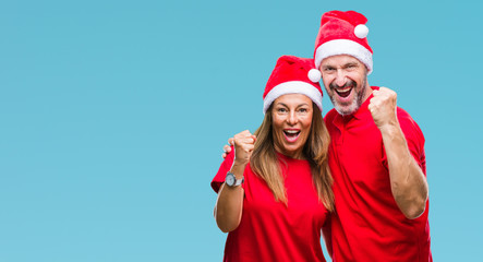 Middle age hispanic couple wearing christmas hat over isolated background celebrating surprised and amazed for success with arms raised and open eyes. Winner concept.