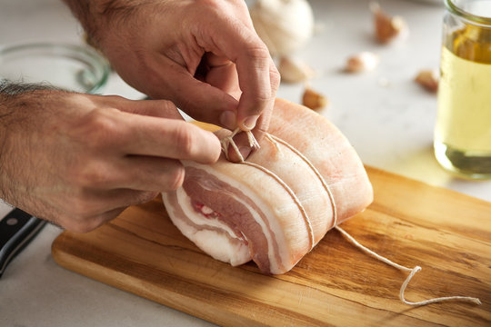 Chef preparing pork belly on board.