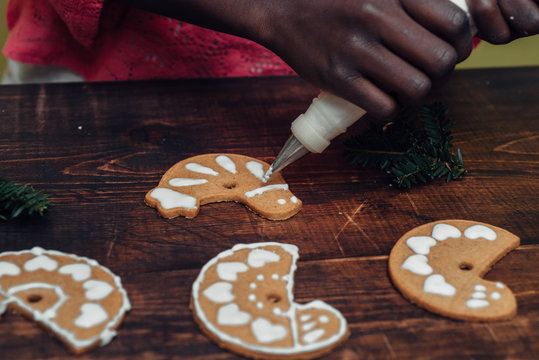 Black girl's hands decorating Christmas cookies