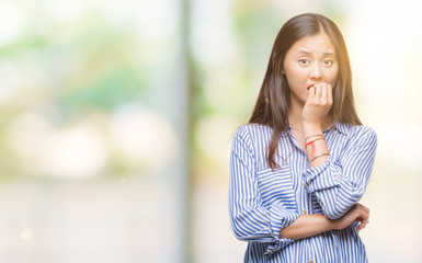 Young asian woman over isolated background looking stressed and nervous with hands on mouth biting nails. Anxiety problem.