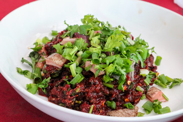 Raw beef salad in a white plate placed on the table.