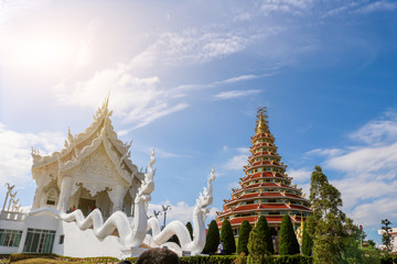 The white Thai chapel and the Chinese pagoda are side by side with a spotlight located in the sun in the daytime.Wat Huayplakang Chiangrai Thailand : 9 November 2018.