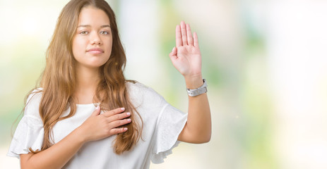 Young beautiful brunette business woman over isolated background Swearing with hand on chest and open palm, making a loyalty promise oath