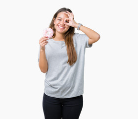 Obraz na płótnie Canvas Young beautiful woman eating pink donut over isolated background with happy face smiling doing ok sign with hand on eye looking through fingers