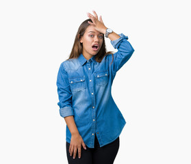 Young beautiful brunette woman wearing blue denim shirt over isolated background surprised with...