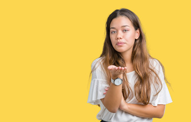 Young beautiful brunette business woman over isolated background looking at the camera blowing a kiss with hand on air being lovely and sexy. Love expression.