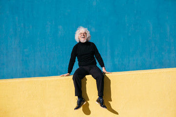Laughing senior man on bright wall