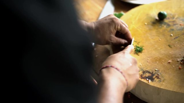 Cutting a selection of healthy nutritious vegetables on wooden chopping board with Balinese Blakas in Indonesia