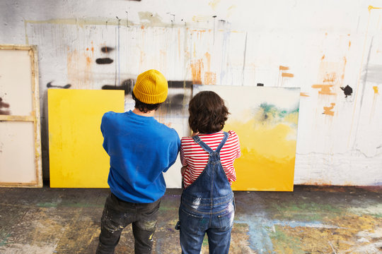 Artists In Casuals Looking At Paintings In Studio