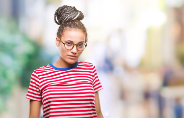 Young braided hair african american girl wearing glasses over isolated background with serious expression on face. Simple and natural looking at the camera.