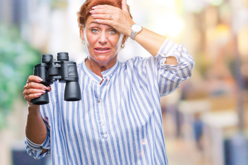 Senior caucasian woman looking through binoculars over isolated background stressed with hand on head, shocked with shame and surprise face, angry and frustrated. Fear and upset for mistake.